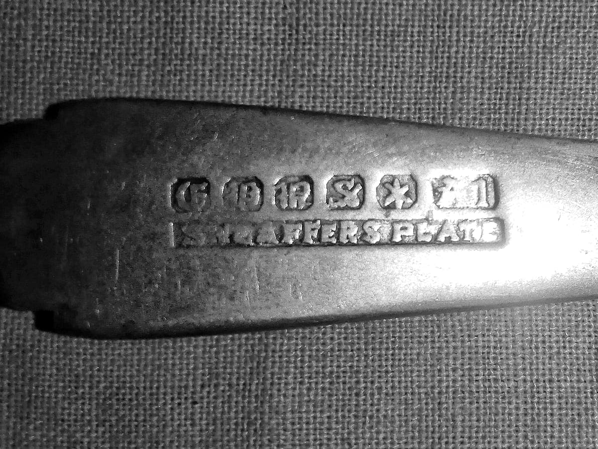 Close-up of a row of small marks struck into the handle of an old spoon
